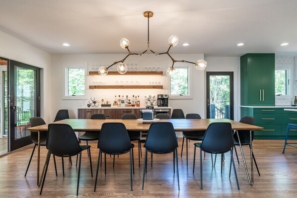 A modern kitchen with a wooden dining table, black chairs, and a unique chandelier.
