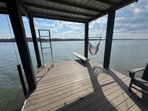 A wooden deck with a hammock, a bench, and a ladder.