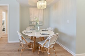 A dining area with a round table, white chairs, and a chandelier. - Beautifully Updated 9th Floor in Silver Shells St. Lucia! (Destin)