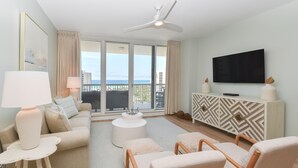 Ein modernes Hotelzimmer mit Balkon, einem Flachbildfernseher, einem gemusterten Schrank und einer gemütlichen Sitzecke.