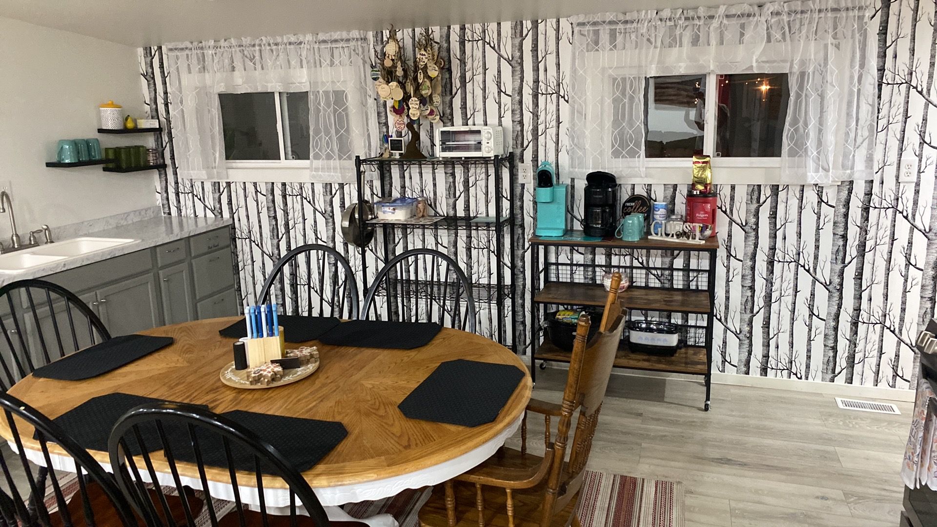 A dining area with a round table, chairs, and a kitchen area with a microwave and coffee maker.