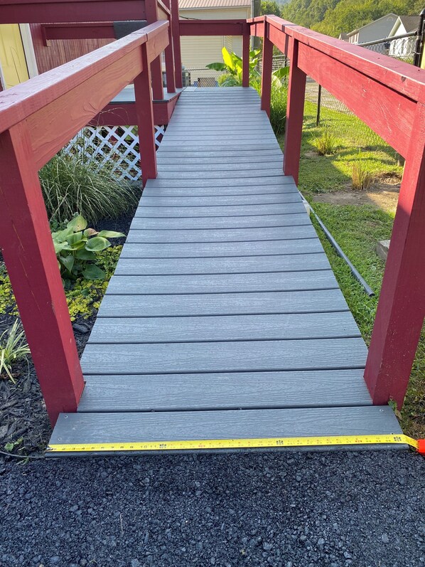 A wooden deck with red railings leading to a house.