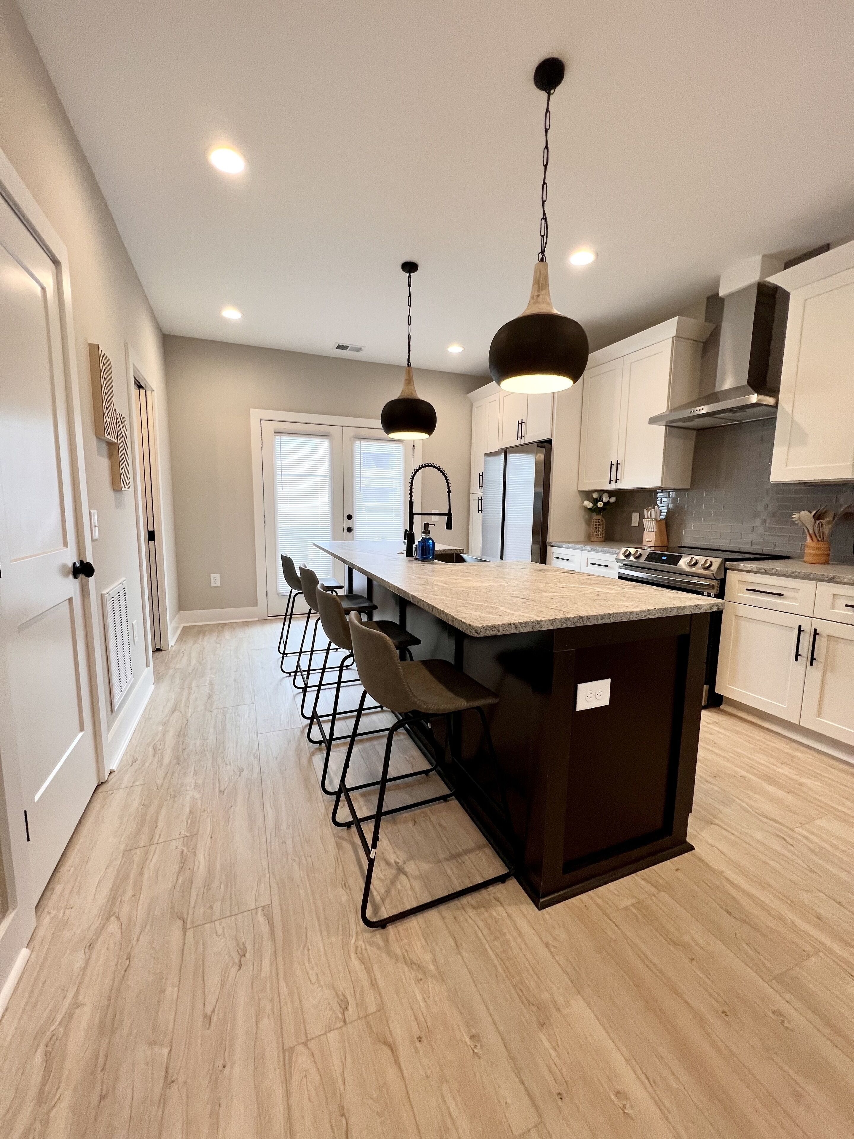A modern kitchen with a central island, pendant lighting, and a stainless steel range hood.