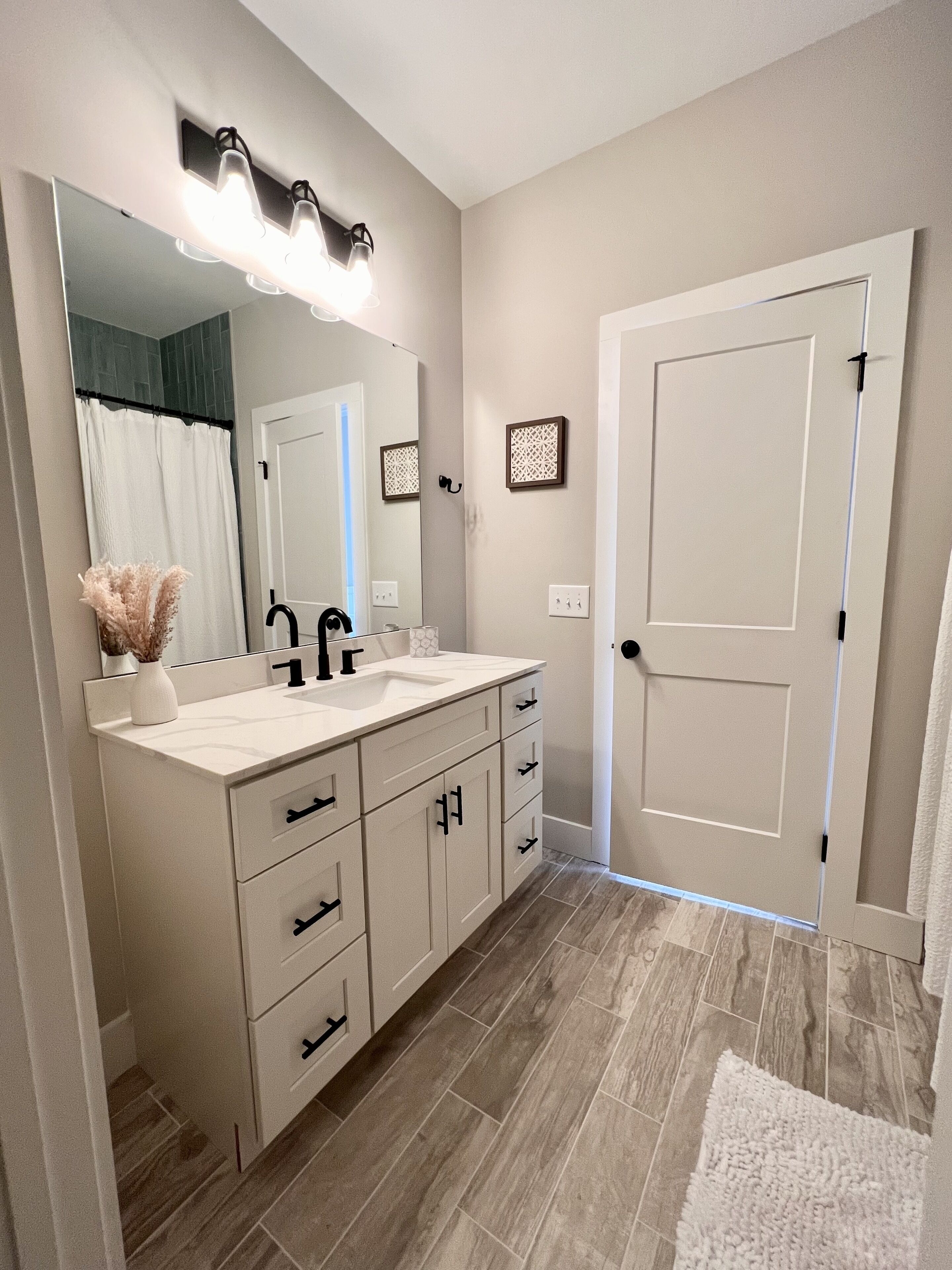 A modern bathroom with a double sink vanity, a large mirror, and a shower curtain.