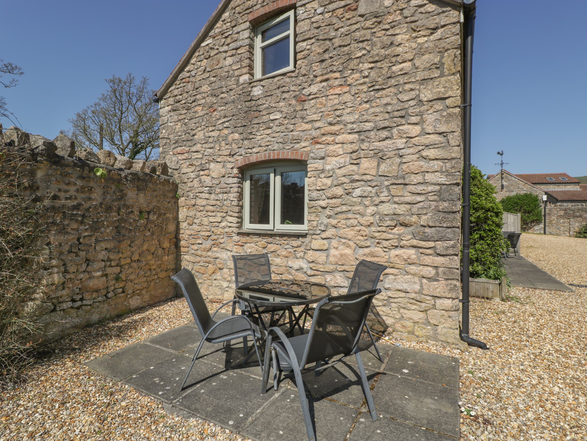 A stone building with a patio area featuring a table and chairs.