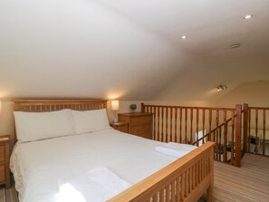 A bedroom with a wooden bed, nightstands, a lamp, and a staircase. - Sunnyside (Weston-super-Mare)
