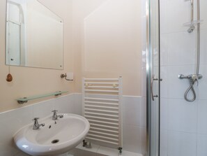 A bathroom with a white sink, mirror, and shower. - Sunnyside (Weston-super-Mare)