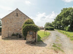 A stone building with a gravel path leading to it, surrounded by greenery and trees. - Sunnyside (Weston-super-Mare)