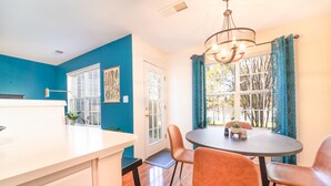 A bright kitchen with a white island, blue walls, and a dining area with a round table and orange chairs.