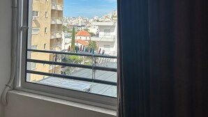 A hotel room with a large window, a view of the cityscape, and a sign with the hotel's name.