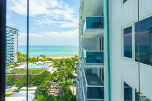 A high-rise hotel with a view of a beach and pool area.