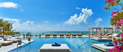 A poolside area with lounge chairs and a view of the ocean.