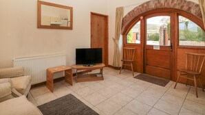 Ein gemütliches Wohnzimmer mit Fernseher, einem Holzstuhl, einer Couch und einem Kamin.