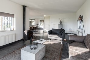 Een moderne woonkamer met een open haard, een bank, een salontafel en een eethoek op de achtergrond.