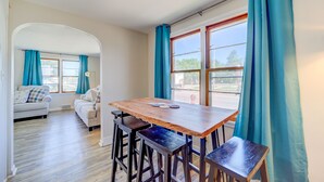 A dining area with a wooden table and bar stools, a sofa, and a window with curtains. - Whitehall Cottages (Whitehall)