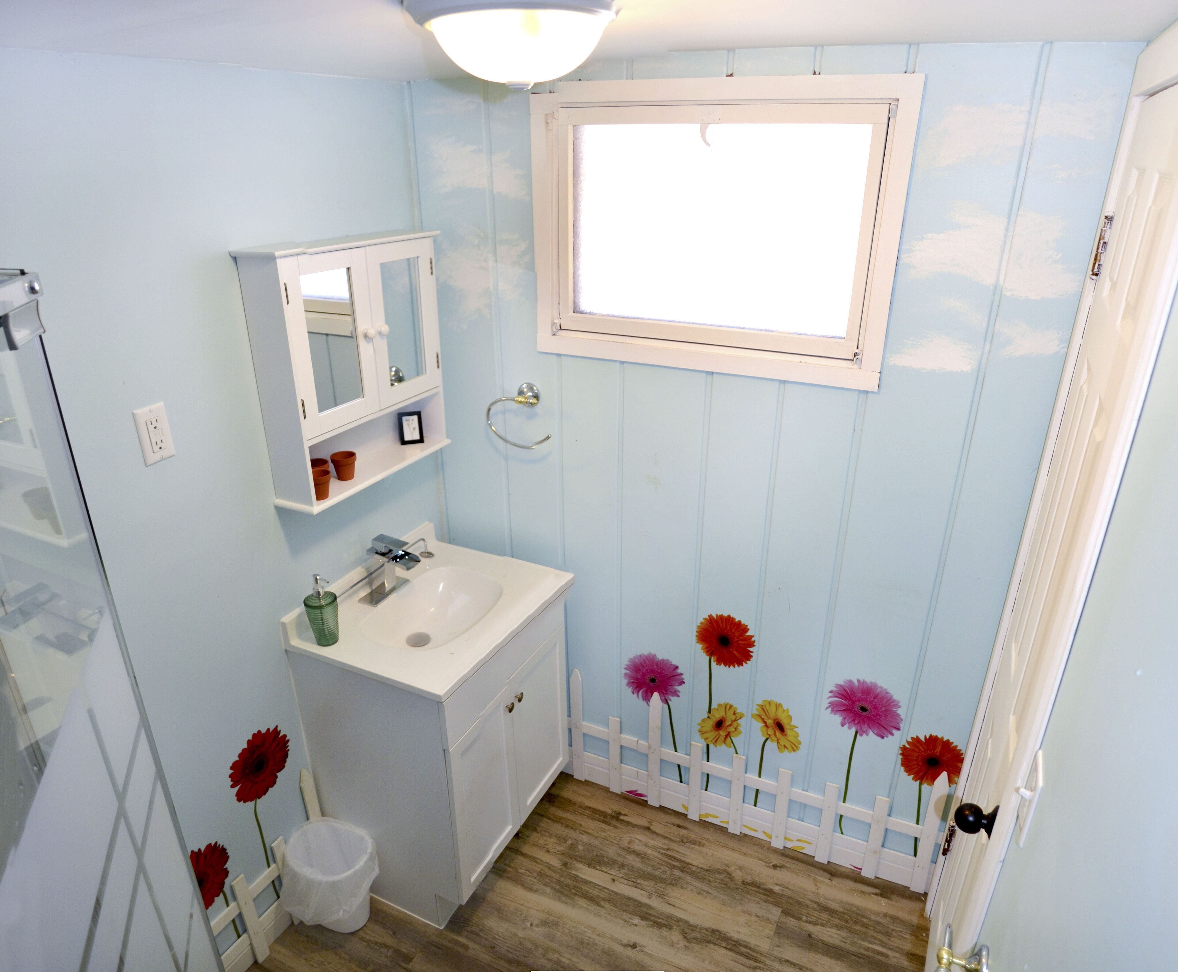 A bathroom with a sink, mirror, and window.