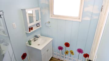 A bathroom with a sink, mirror, and window.