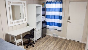 A room with a white desk, black office chair, white wardrobe, and a blue and white striped shower curtain. - Whitehall Cottages (Whitehall)