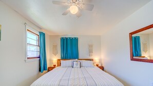 A bedroom with a bed, a ceiling fan, a window with curtains, and a mirror on the wall. - Whitehall Cottages (Whitehall)