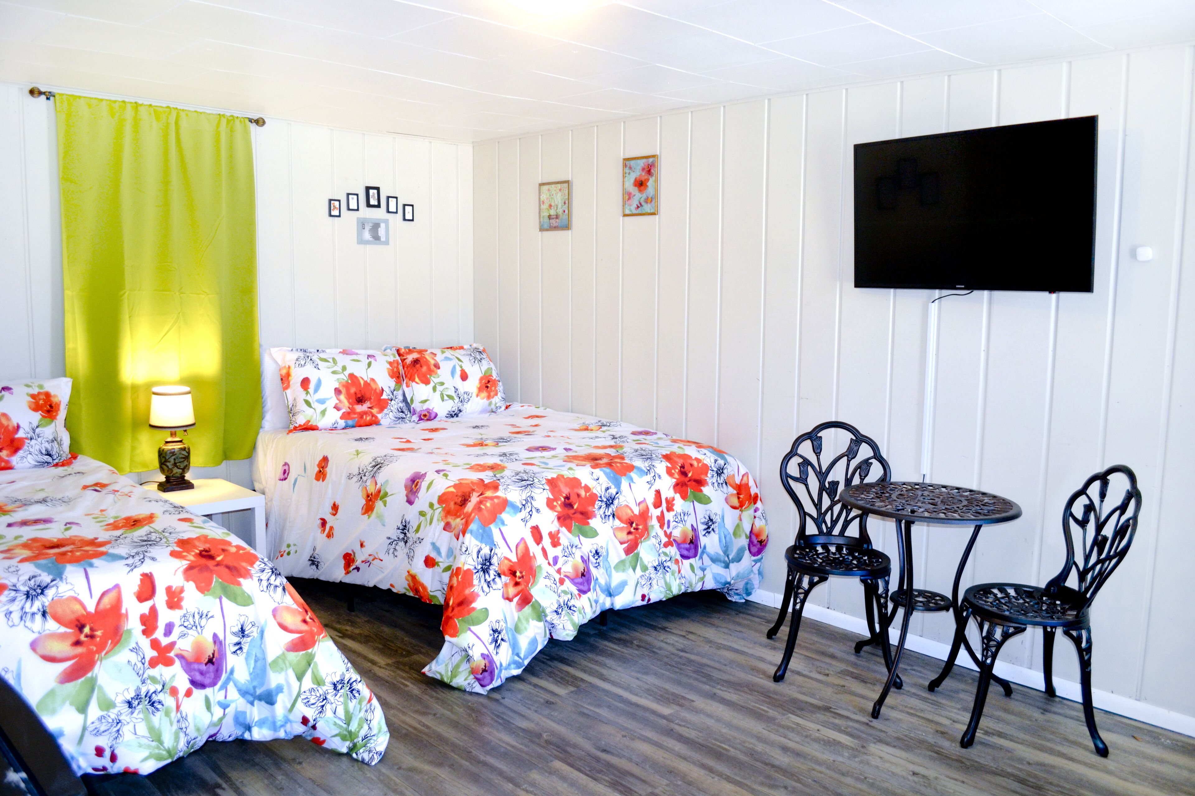 A room with two beds, a TV, and a table with chairs.