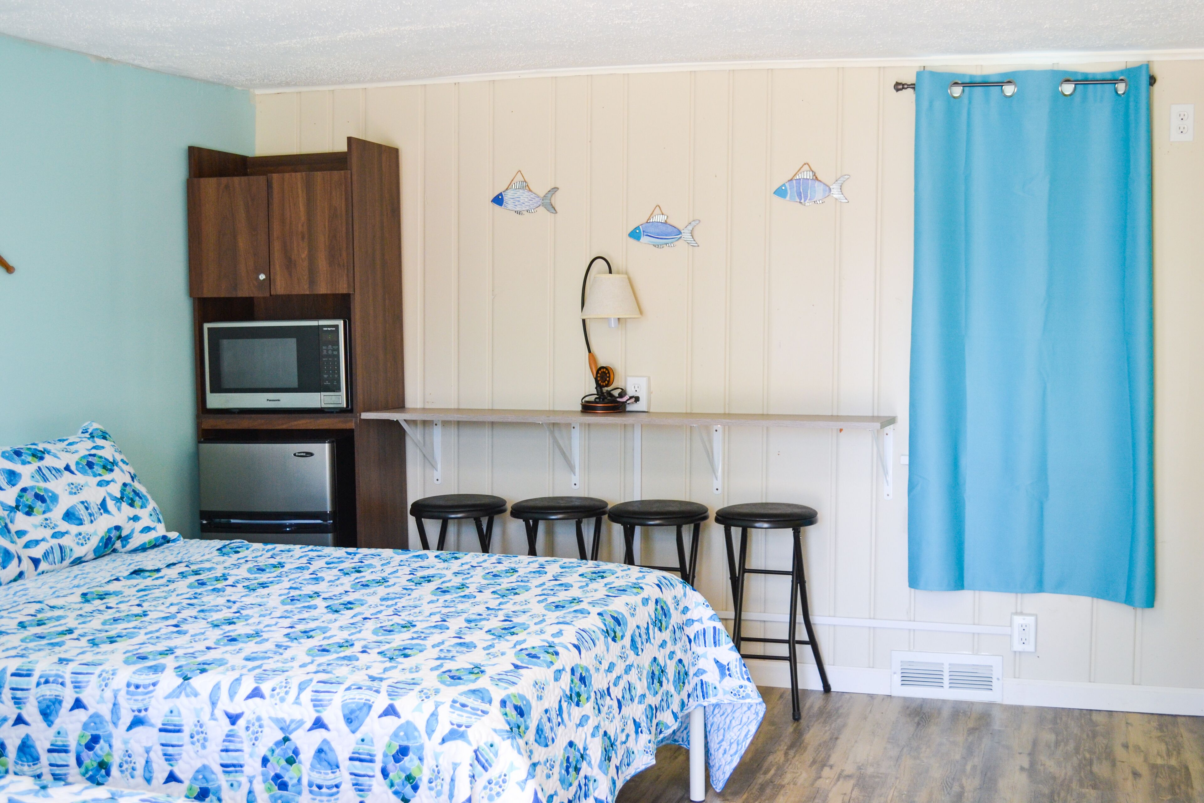 A bedroom with a bed, a kitchenette with a microwave, and a bathroom with a shower curtain.