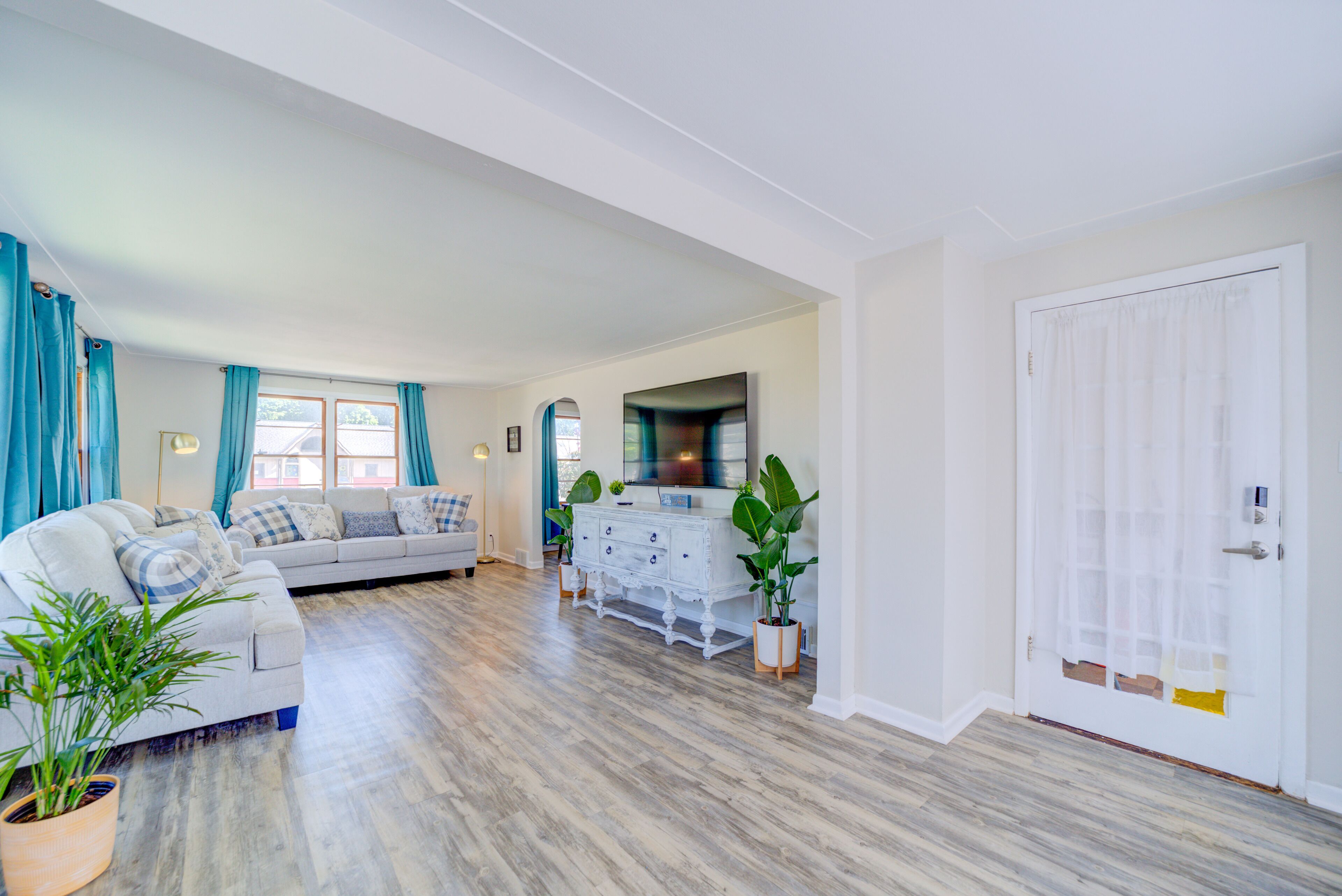 Een ruime woonkamer met een zithoek, een witte kast en een grote spiegel.