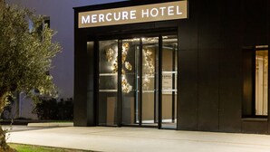 The exterior of the Mercure Hotel with a modern facade, large glass entrance, and a sign above the doors. - Mercure Toulouse Aéroport Blagnac (Blagnac)