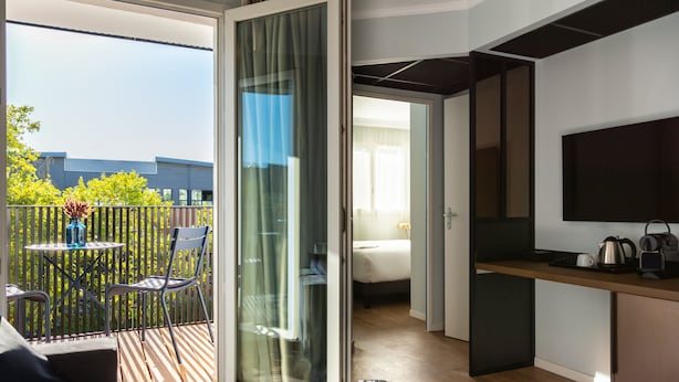 A modern room with a balcony, a bed, a desk, and a TV. - Mercure Toulouse Aéroport Blagnac (Blagnac)
