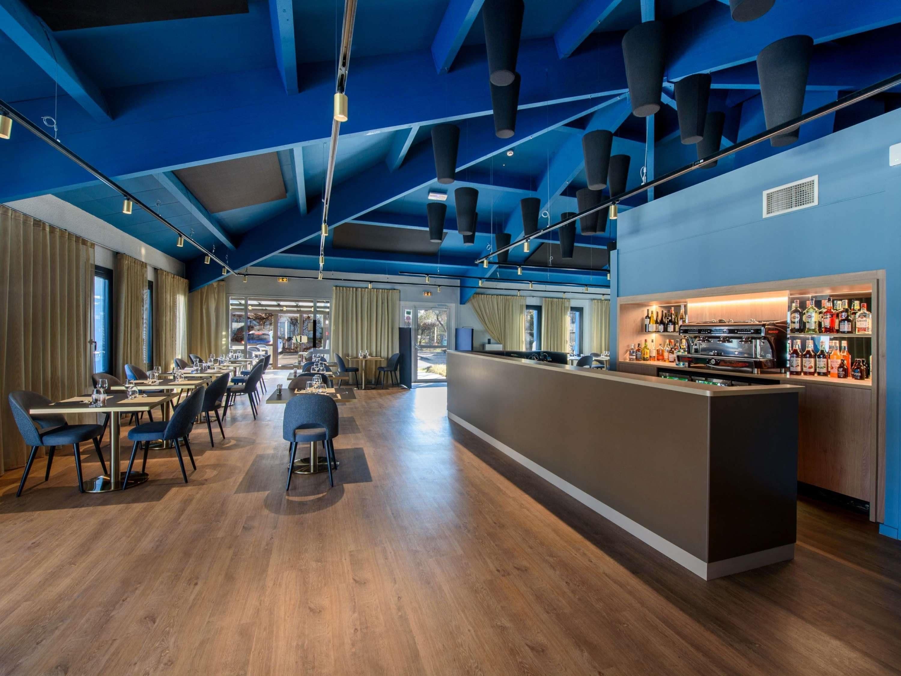 Een moderne bar met een lange toonbank, een koffieapparaat en diverse flessen.