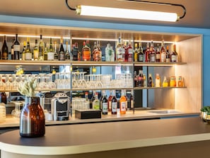 Un espace bar avec des étagères remplies de bouteilles d’alcool et de verres.