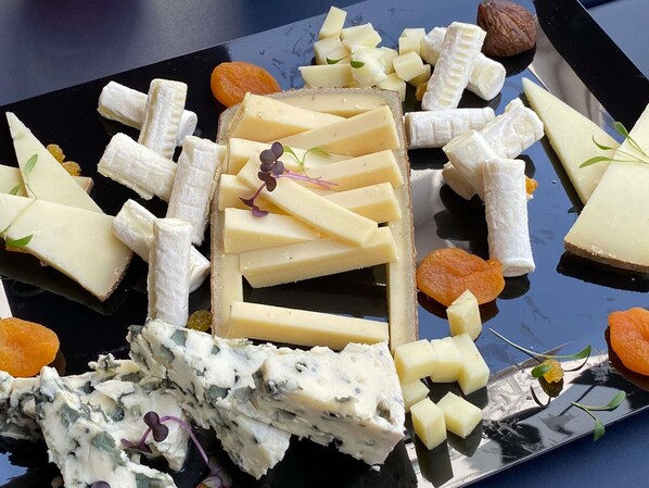 A variety of cheeses and fruits on a black plate.