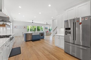 Una cocina moderna con electrodomésticos de acero inoxidable, suelo de madera y vistas al exterior.