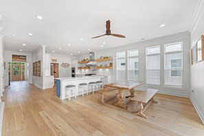 A spacious kitchen with a central island, bar stools, and a dining table.