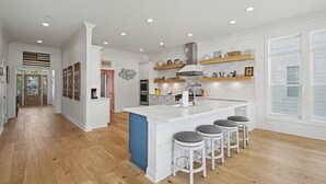 Una cocina moderna con una isla central, taburetes de bar y estanterías empotradas.