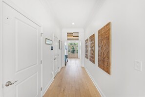 A hallway with white walls, wooden flooring, and decorative panels on the walls.