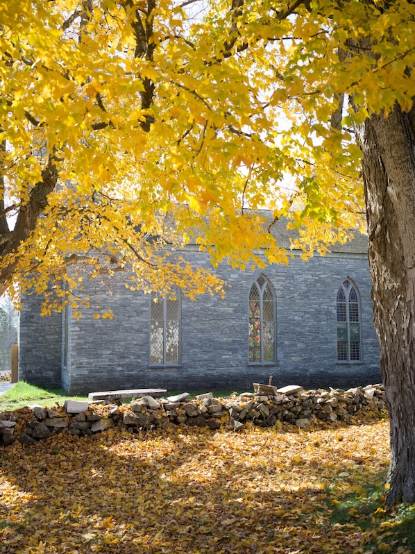 A stone building with arched windows and a stone wall in front.