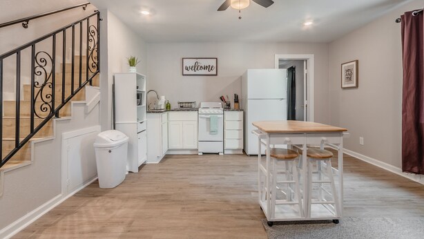 Une cuisine moderne avec des meubles blancs, un îlot central et un ventilateur de plafond.