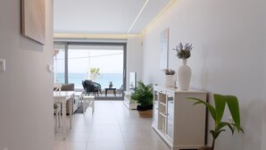 A modern living room with a view of the sea, a dining area, and a white cabinet with plants. - beach deluxe house  (Kos)