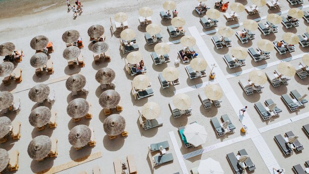 An aerial view of a beach with rows of sun loungers and thatched umbrellas. - beach deluxe house  (Kos)
