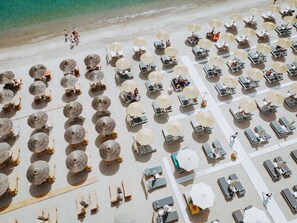 An aerial view of a beach with rows of sun loungers and thatched umbrellas. - beach deluxe house (Kos)