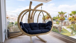 A hanging chair with a cushioned seat and wooden frame, suspended from a circular wooden structure. - beach deluxe house  (Kos)