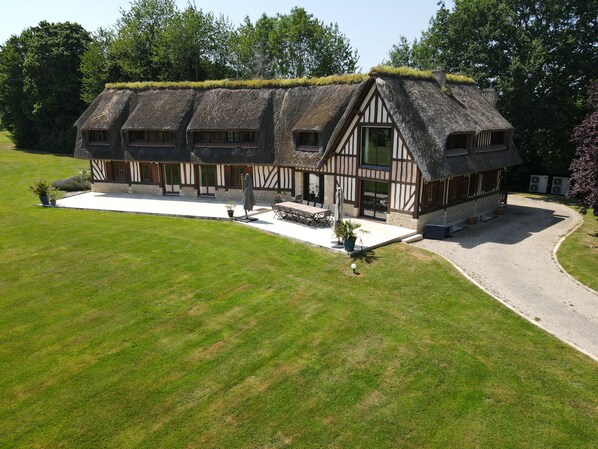 A traditional thatched-roof building with a white exterior and timber framing, surrounded by a well-maintained lawn.