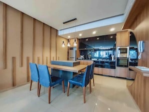 Una cocina moderna con armarios de madera, una isla central y una zona de comedor con sillas azules.