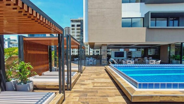 A rooftop pool area with a wooden deck, lounge chairs, and a pool. - Spectacular + cozy brand new apartment! (Santa Cruz de la Sierra)