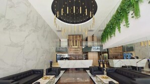 A modern lobby with marble walls, black leather sofas, a central reception desk, and a hanging plant. - Spectacular + cozy brand new apartment! (Santa Cruz de la Sierra)