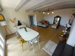 Una sala de estar moderna con comedor, un sofá, una mesa de centro y una escalera que sube a otro nivel.