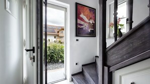 Ein modernes Interieur mit einer Treppe, einer zur Außenseite führenden Tür und einem gerahmten Kunstwerk an der Wand.