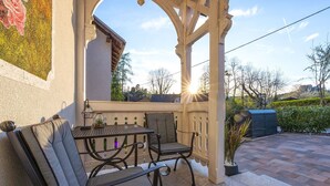 Eine Außenpatio mit einer Pergola, zwei Stühlen, einem Tisch und einem Blumentopf.