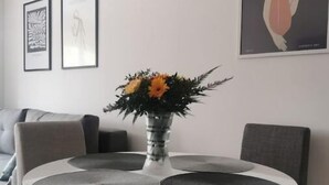 Et moderne spiseområde med et rundt bord, grå stole og en vase med blomster.