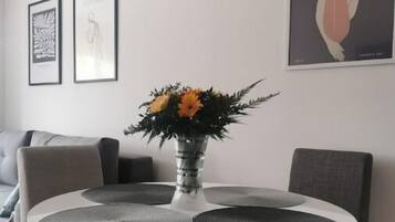Un comedor moderno con una mesa redonda, sillas grises y un jarrón con flores.